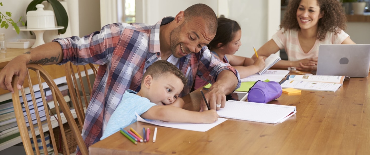 Parents Helping Children With Homework At Table